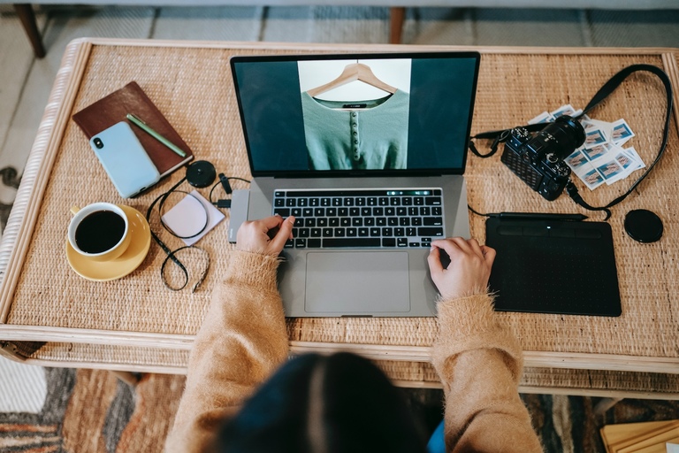Eine Person am Laptop  am Tisch mit Bild von einem Pullover